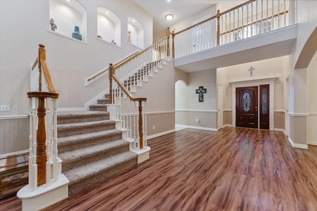 5811 Tremont Dr, Cove, TX 77523 - entrance foyer with arched walkways, stairs, a towering ceiling, wood finished floors, and baseboards