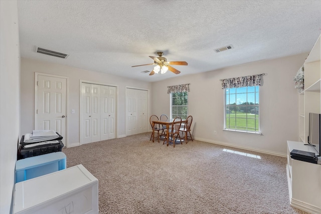 interior space with a ceiling fan, visible vents, a textured ceiling, and baseboards