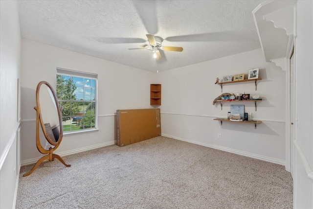 empty room featuring light carpet, baseboards, a ceiling fan, and a textured ceiling