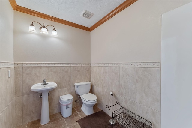 half bathroom featuring crown molding, visible vents, toilet, a textured ceiling, and tile patterned floors