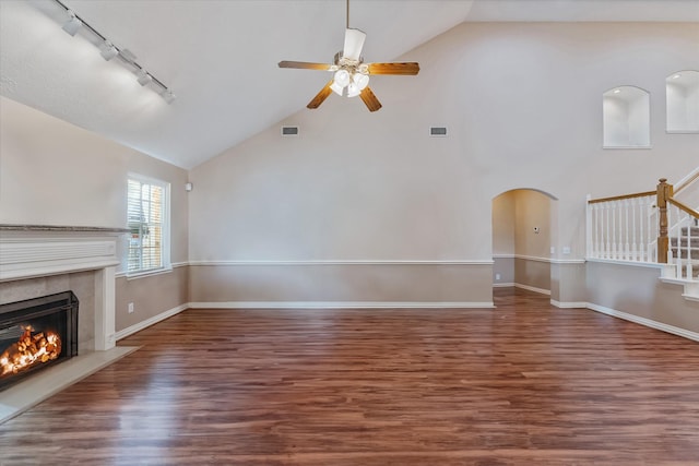 unfurnished living room featuring a ceiling fan, arched walkways, visible vents, and a tiled fireplace