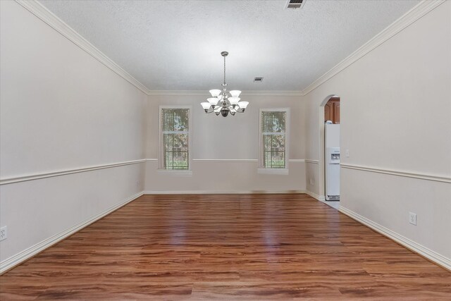 unfurnished dining area with crown molding, arched walkways, a chandelier, and wood finished floors