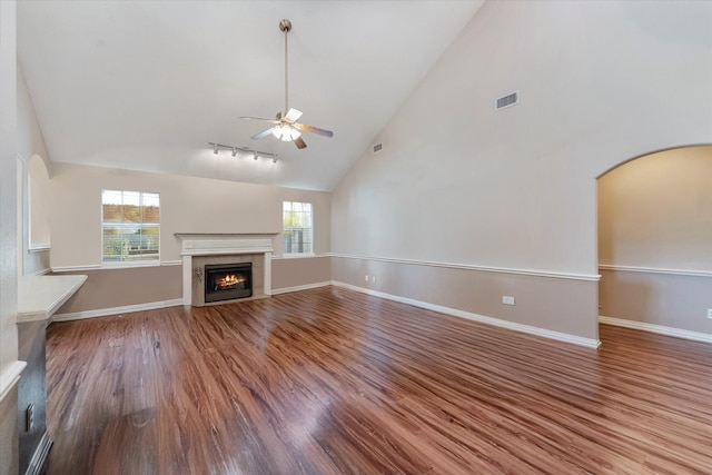 5811 Tremont Dr, Cove, TX 77523 - unfurnished living room featuring ceiling fan, wood finished floors, high vaulted ceiling, a tiled fireplace, and arched walkways