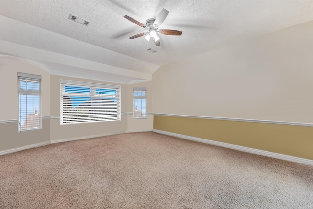 spare room featuring visible vents, baseboards, ceiling fan, light colored carpet, and a textured ceiling