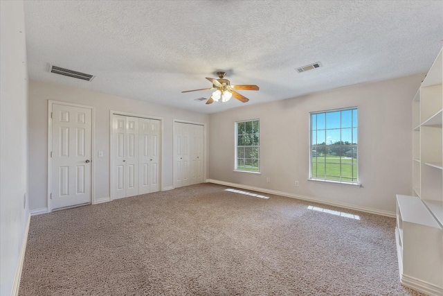 unfurnished bedroom featuring carpet flooring, multiple closets, visible vents, and baseboards