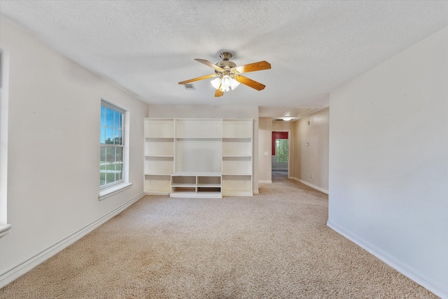 spare room featuring a ceiling fan, a textured ceiling, light colored carpet, and attic access