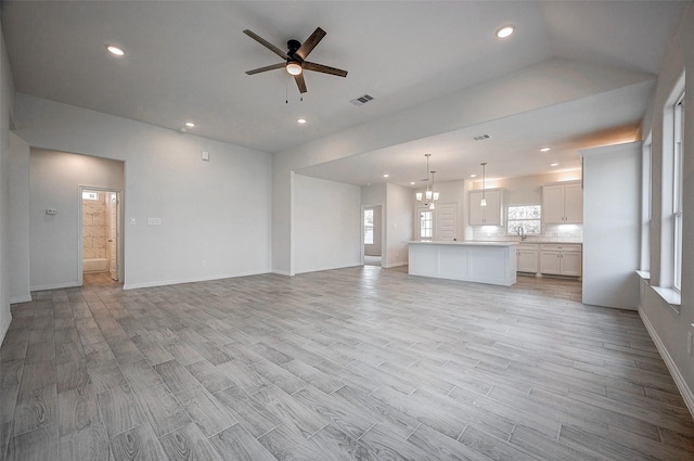 24690 Galway St, Hempstead, TX 77445 - unfurnished living room with light wood finished floors, visible vents, a wealth of natural light, and ceiling fan with notable chandelier