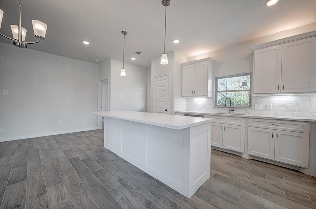 24690 Galway St, Hempstead, TX 77445 - kitchen featuring decorative light fixtures, light countertops, white cabinetry, a kitchen island, and a sink