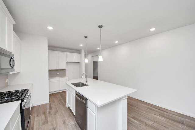 24727 Harrow Meadow Dr, Katy, TX 77493 - kitchen with an island with sink, light wood-style flooring, decorative backsplash, stainless steel appliances, and a sink