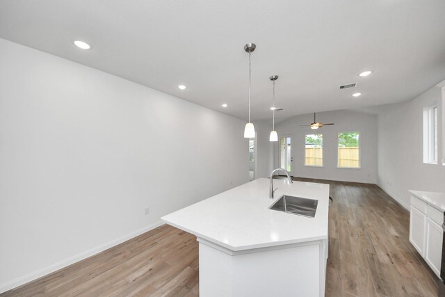 24727 Harrow Meadow Dr, Katy, TX 77493 - kitchen with light wood-style floors, white cabinetry, light countertops, a sink, and open floor plan