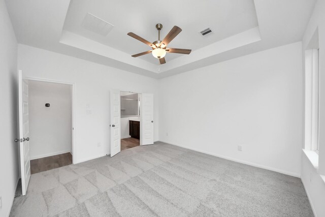 24727 Harrow Meadow Dr, Katy, TX 77493 - unfurnished bedroom with ensuite bathroom, a tray ceiling, visible vents, carpet floors, and baseboards