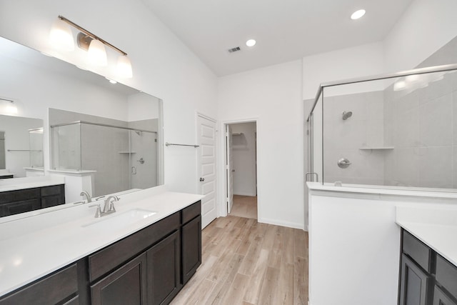 24727 Harrow Meadow Dr, Katy, TX 77493 - bathroom featuring visible vents, a sink, a shower stall, wood finished floors, and two vanities