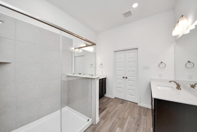 24727 Harrow Meadow Dr, Katy, TX 77493 - bathroom featuring two vanities, a shower stall, visible vents, wood finished floors, and a sink