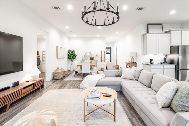 living room featuring an inviting chandelier, visible vents, wood finished floors, and recessed lighting