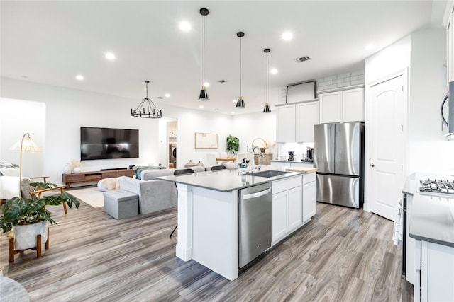 kitchen featuring stainless steel appliances, visible vents, open floor plan, white cabinets, and a kitchen island with sink