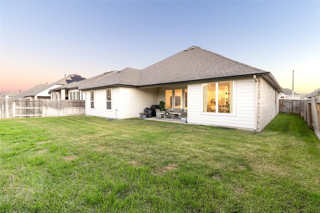 back of property featuring a patio area, a shingled roof, a fenced backyard, and a yard