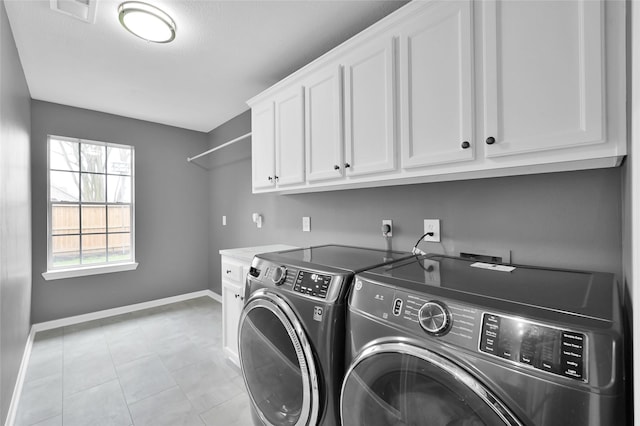 clothes washing area featuring light tile patterned floors, visible vents, cabinet space, washing machine and dryer, and baseboards