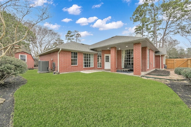 rear view of house featuring a patio, cooling unit, brick siding, fence, and a lawn