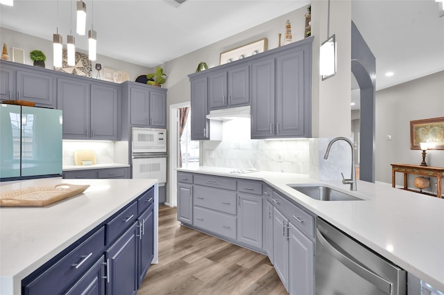 kitchen featuring white appliances, light countertops, and a sink