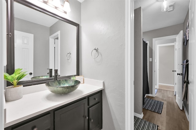 bathroom featuring baseboards, visible vents, wood finished floors, and vanity