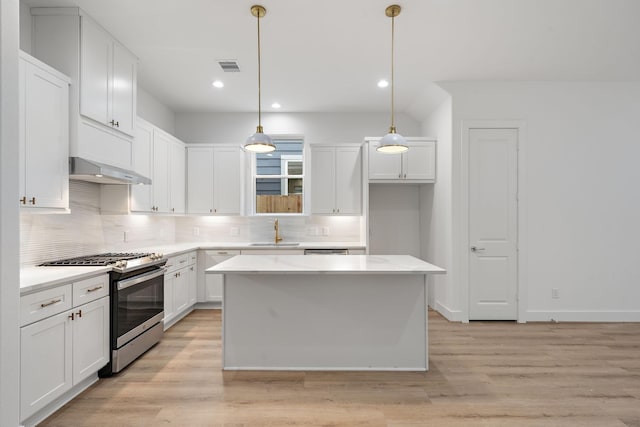 kitchen with hanging light fixtures, white cabinets, and gas stove