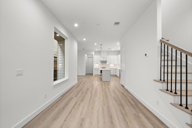 unfurnished living room with recessed lighting, visible vents, light wood-type flooring, baseboards, and stairs