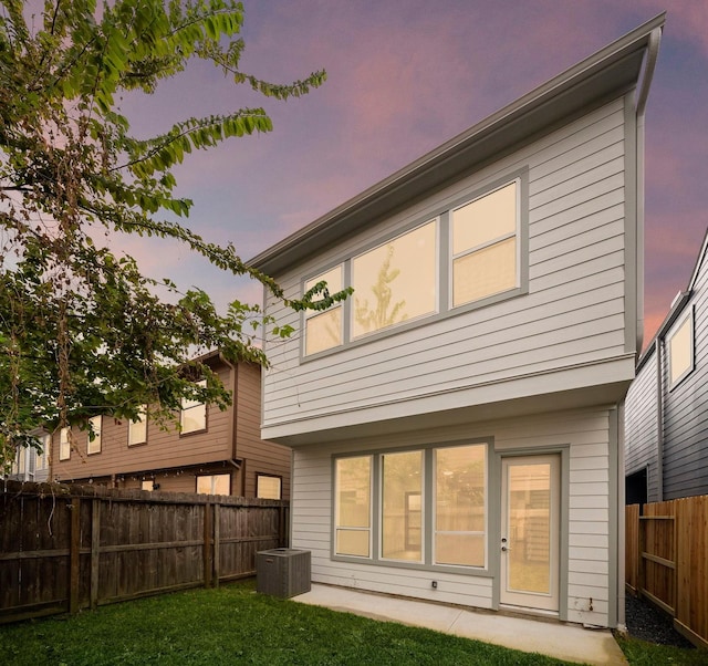 rear view of property with cooling unit, a patio area, a fenced backyard, and a lawn