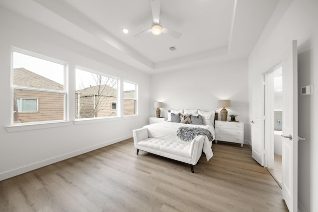 bedroom featuring a raised ceiling, visible vents, ceiling fan, wood finished floors, and baseboards