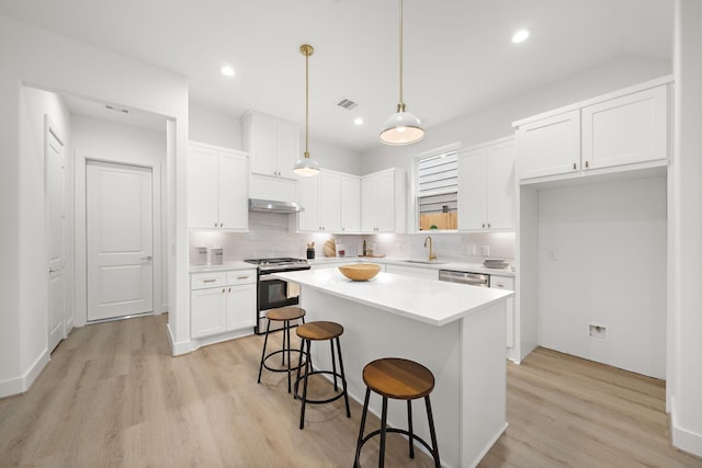 kitchen with a kitchen island, appliances with stainless steel finishes, decorative light fixtures, light countertops, and white cabinetry