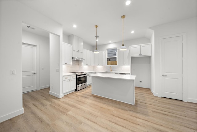 kitchen featuring light countertops, hanging light fixtures, stainless steel gas stove, a kitchen island, and white cabinetry