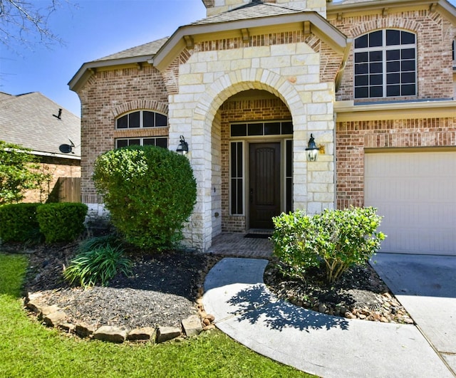 property entrance with a garage, stone siding, and brick siding