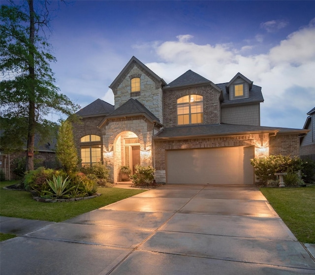 french provincial home featuring brick siding, a front lawn, concrete driveway, and a garage