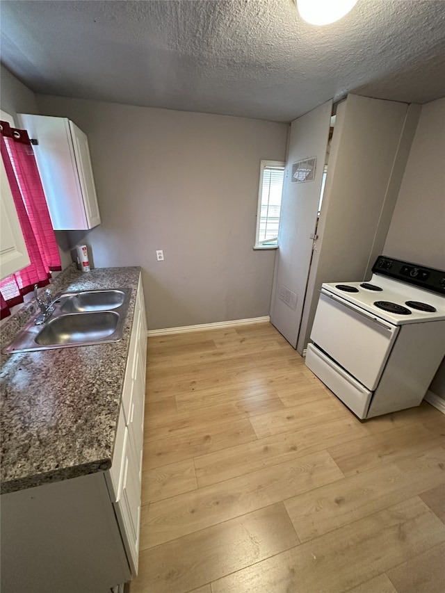 kitchen with dark countertops, light wood-style floors, white cabinets, and white electric range