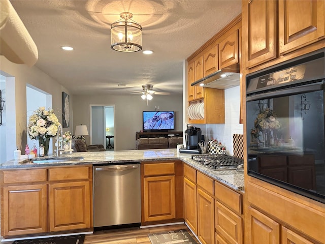 kitchen with stainless steel appliances, open floor plan, brown cabinets, and a sink