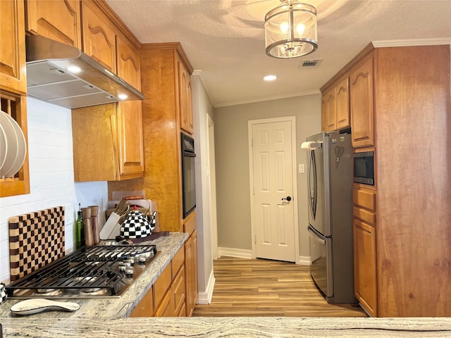 kitchen featuring light stone counters, stainless steel appliances, visible vents, ventilation hood, and brown cabinets