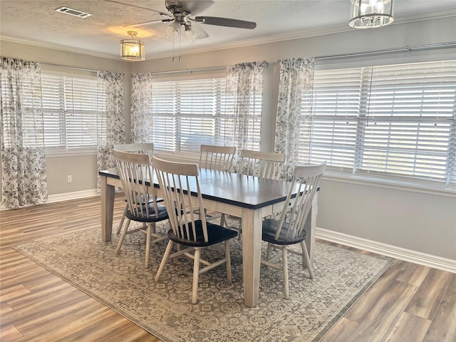 dining space with visible vents, crown molding, and wood finished floors