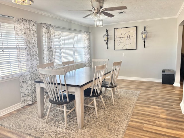 dining room featuring ornamental molding, a textured ceiling, baseboards, and wood finished floors