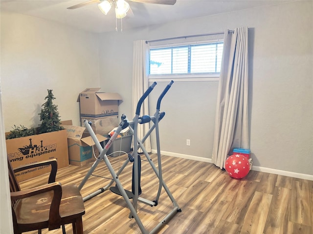 workout area with a ceiling fan, baseboards, and wood finished floors