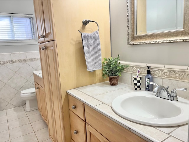 bathroom with toilet, a wainscoted wall, tile patterned floors, vanity, and tile walls