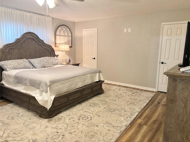 bedroom with a ceiling fan, baseboards, and wood finished floors