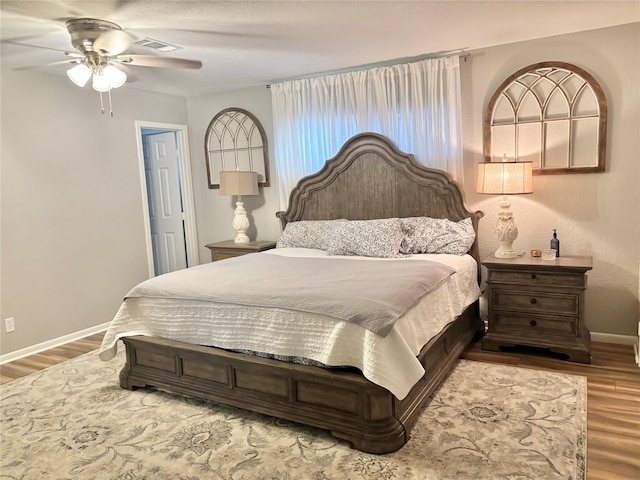 bedroom featuring visible vents, ceiling fan, baseboards, and wood finished floors