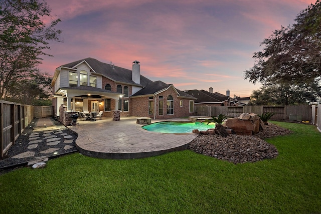 back of property featuring a lawn, a patio area, a fenced backyard, and a fenced in pool