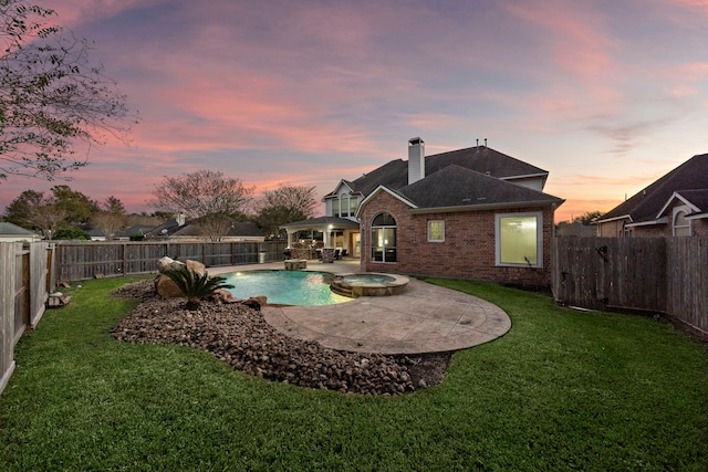 pool at dusk with a pool with connected hot tub, a patio area, a fenced backyard, and a yard