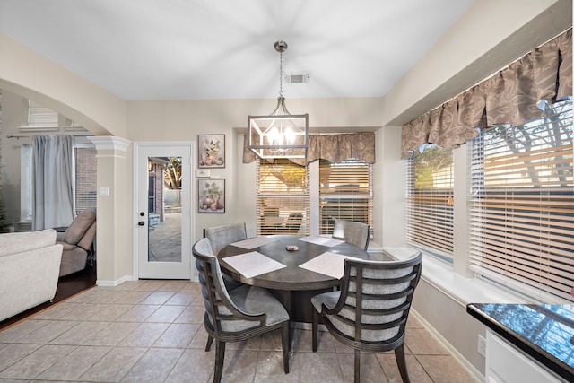 dining space with arched walkways, decorative columns, light tile patterned floors, visible vents, and a chandelier