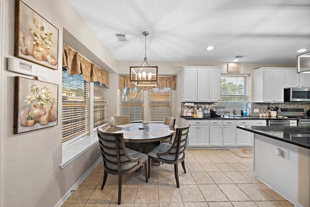 kitchen with appliances with stainless steel finishes, white cabinets, decorative light fixtures, and decorative backsplash