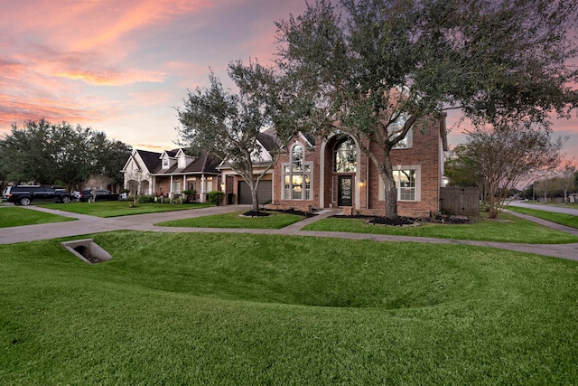 view of front of home with driveway, a lawn, and brick siding