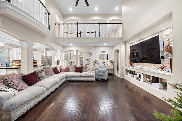 living room with baseboards, decorative columns, arched walkways, and wood finished floors