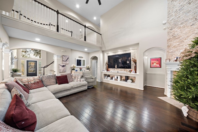 living area with ceiling fan, decorative columns, arched walkways, and dark wood finished floors