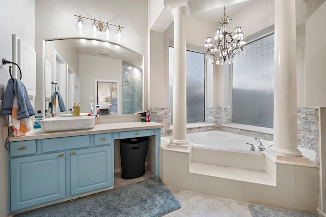 bathroom featuring a garden tub, a notable chandelier, vanity, and ornate columns