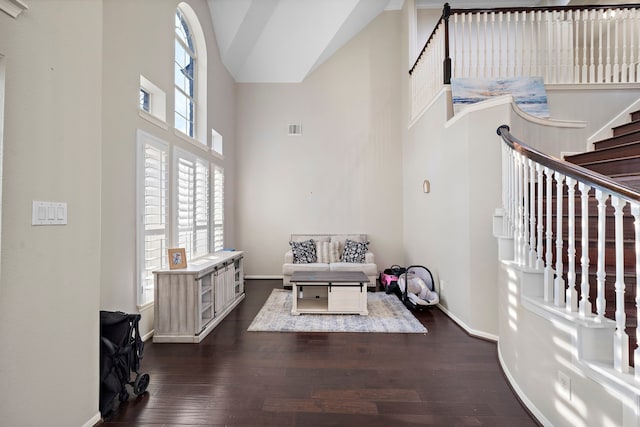 interior space with high vaulted ceiling, dark wood-style flooring, visible vents, baseboards, and stairs